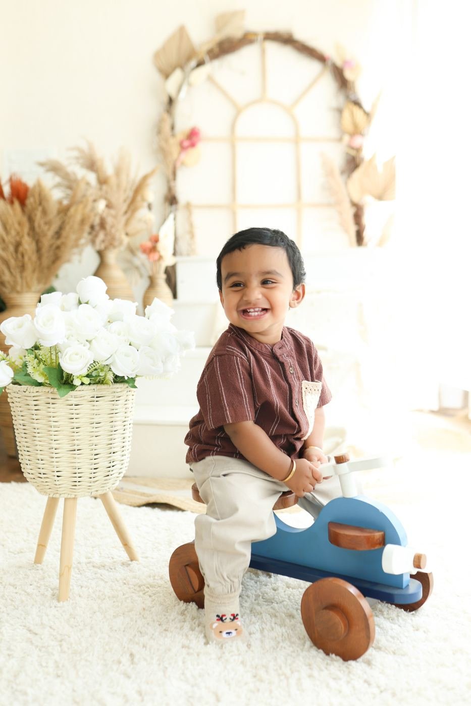 Toddler waving from a toy car in the boho set