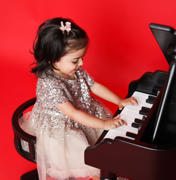 Little girl playing a toy piano in the Little Maestro theme