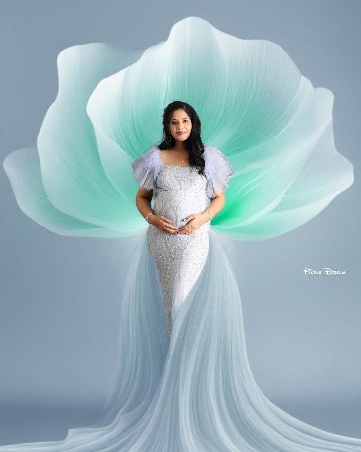 Mother in a white gown framed by a sculpted mint petal backdrop