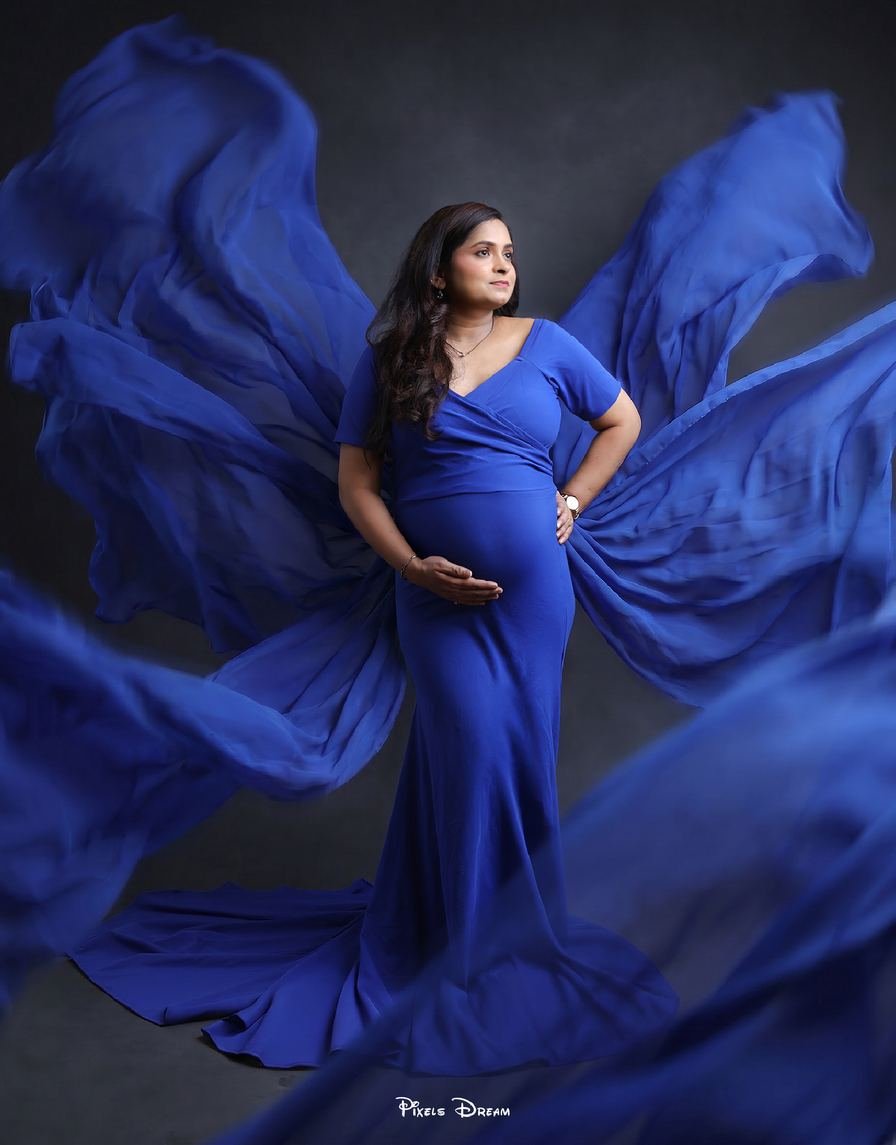 Expectant mother in a royal blue gown with flowing fabric