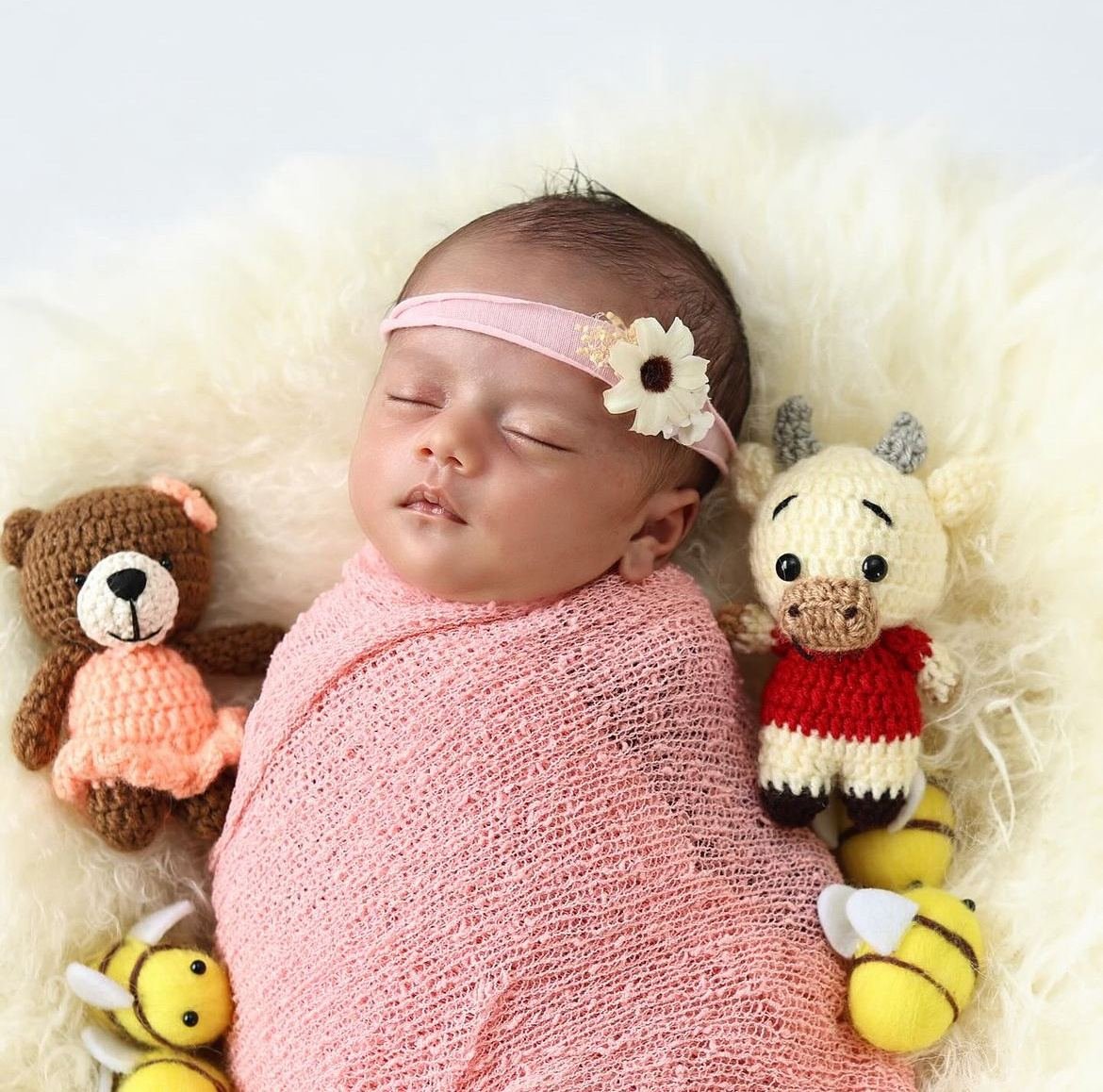 Newborn asleep in a pink wrap with teddies