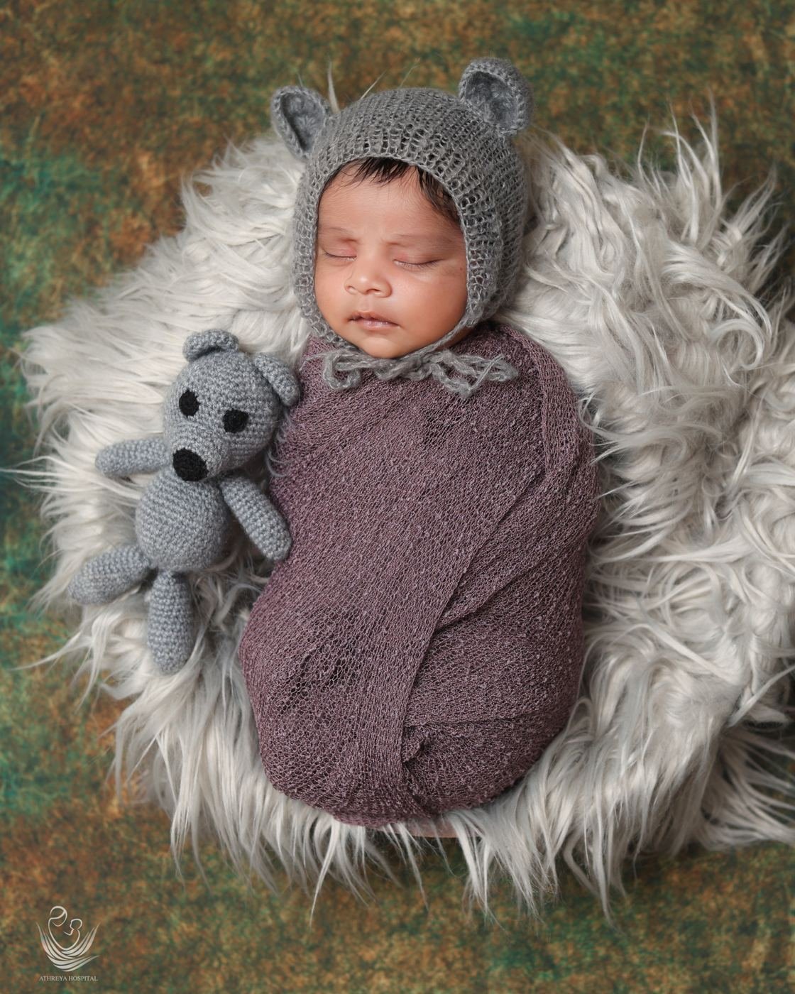 Sleeping newborn in a knitted bear bonnet on soft fur
