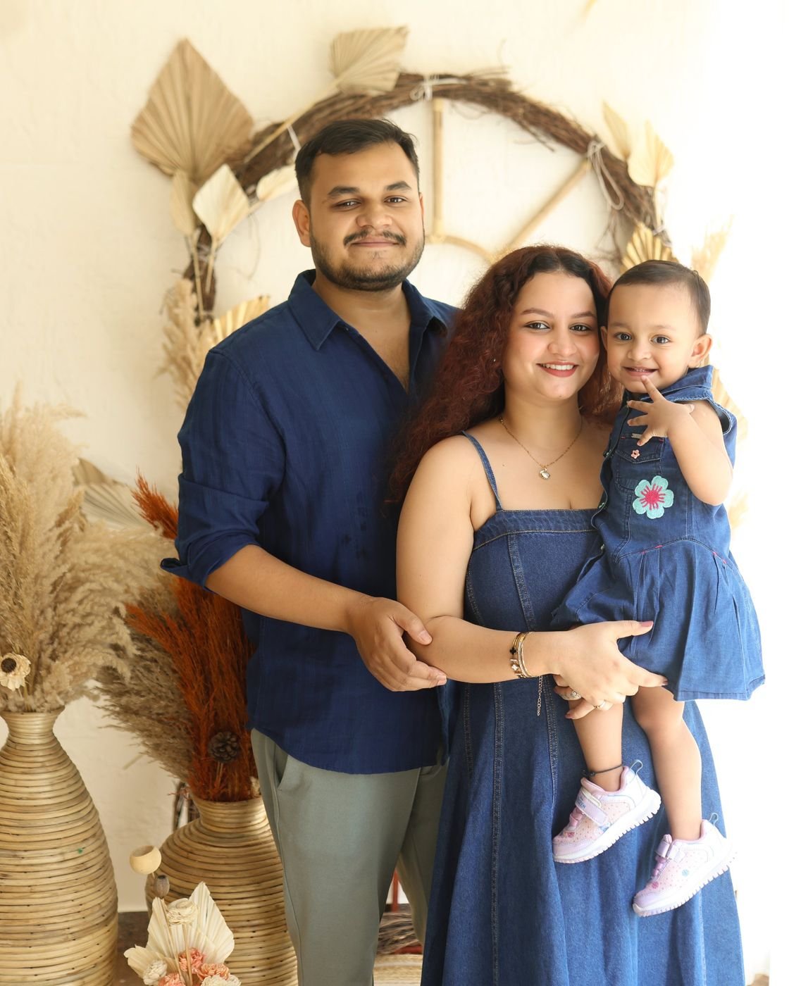 Family of three in denim posing in the Pixels Dream studio with their toddler